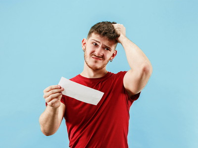 man scratching his head holding a bet slip