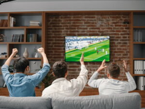 men on coach watching football on tv