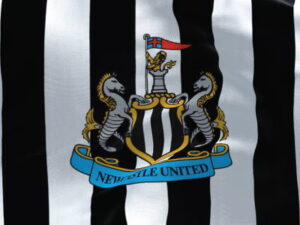 newcastle united crest on black and white striped shirt close up
